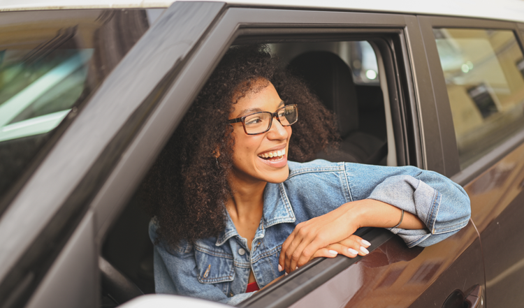 A woman smiling looking out her car window. How to unlock potential tax savings through salary packaging your current car.