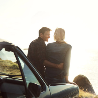 Man and Woman sitting on their car